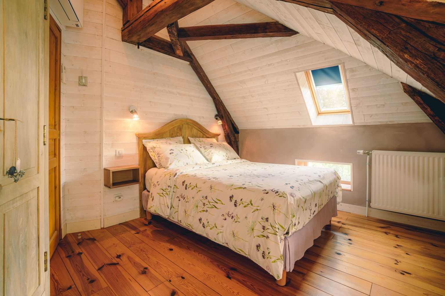 Chambre sous charpente avec lit double et parquet
