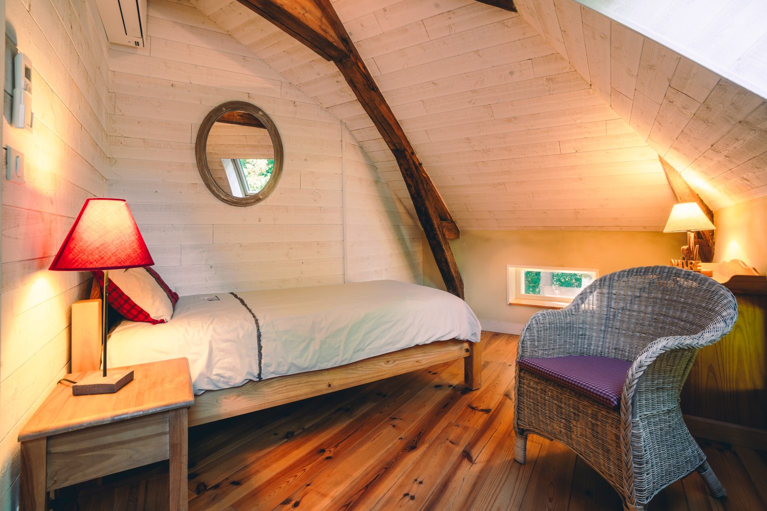 Chambre sous combles avec lampe de chevet et fauteuils en osier