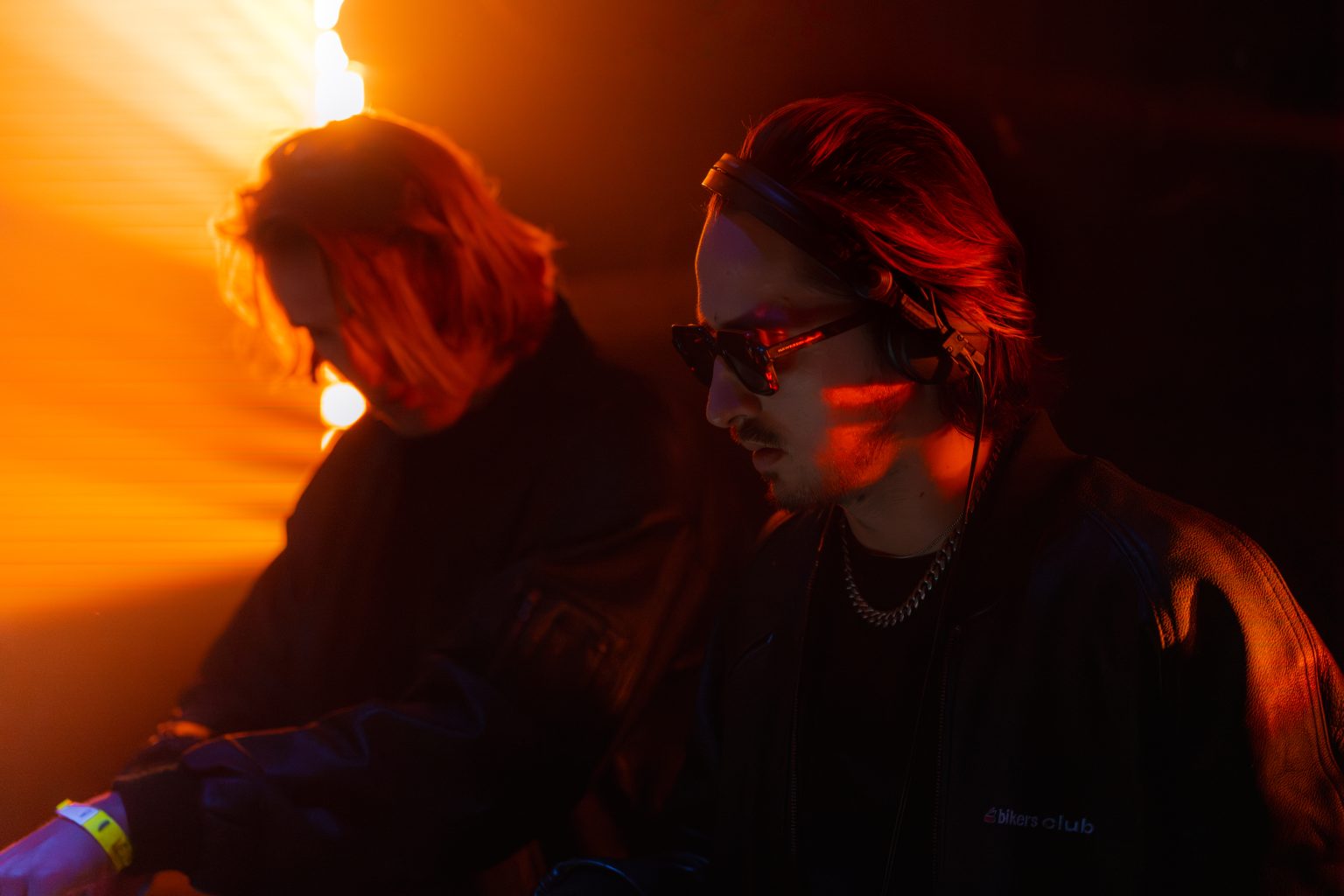 Deux DJ aux platines en contre-jour orange