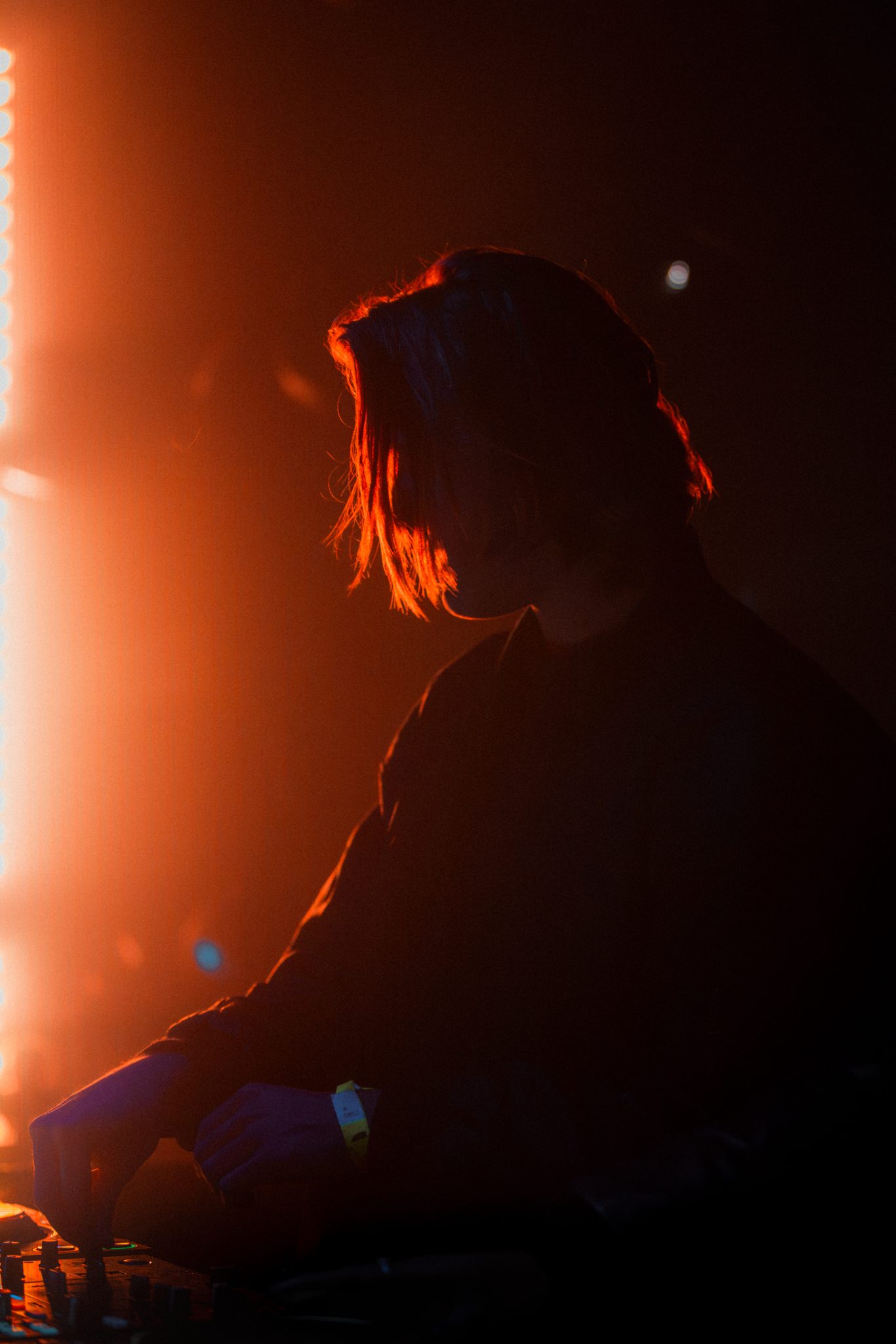 Silhouette d'un DJ dans une lumiere orange, photo de concert