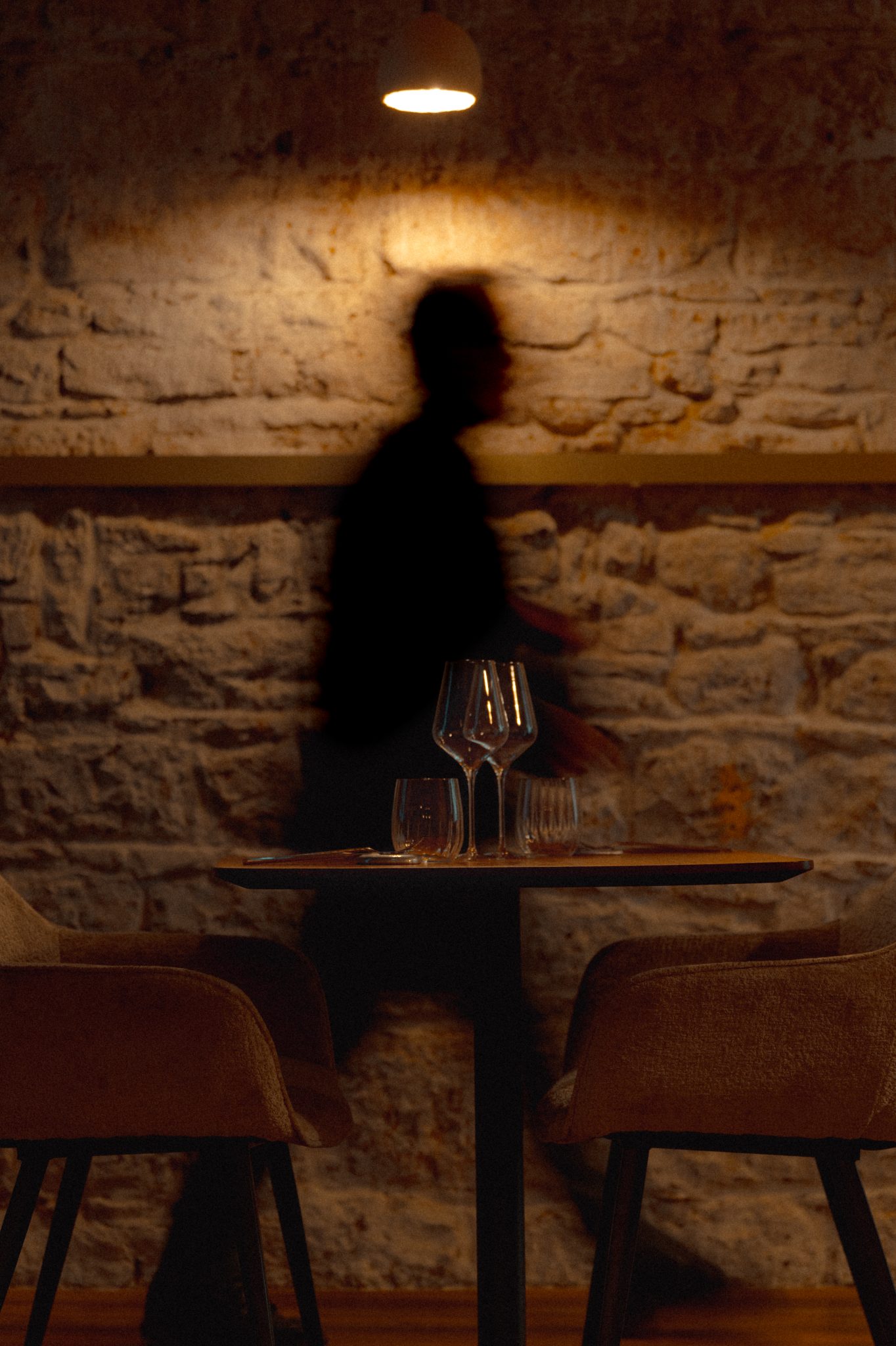 Salle du restaurant Astral en clair-obscur, mur de pierre