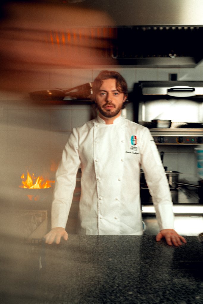 Portrait du chef du restaurant Astral à Lyon, en veste blanche devant sa cuisine