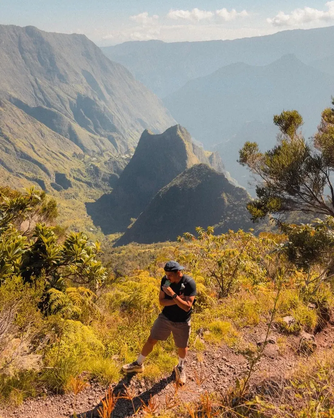 Marcheur sur un sentier de montagne face à un cirque et des pitons rocheux