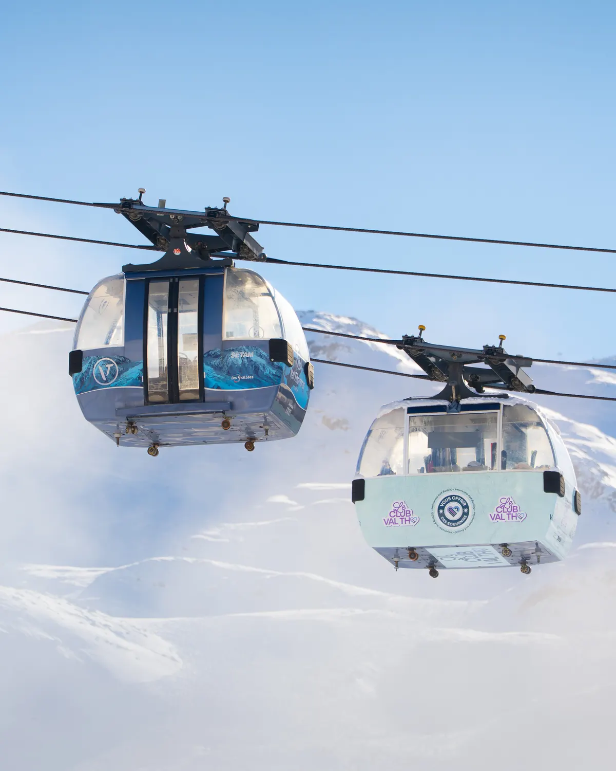 Deux télécabines qui se croisent au-dessus des pistes enneigées d'une station de ski