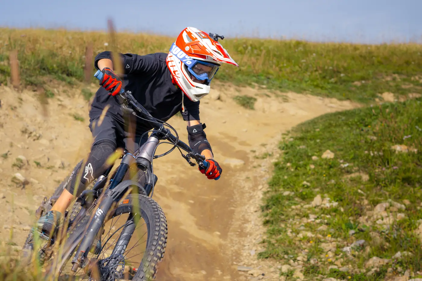 Vététiste en appui dans un virage de terre du bike park des Saisies, casque intégral