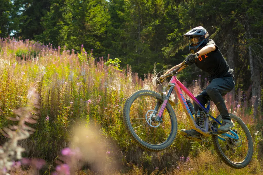 VTTiste en plein saut dans les épilobes, campagne photo pour la station des Saisies