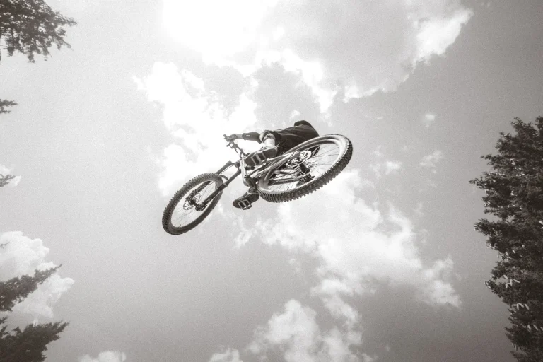 VTTiste en plein saut sur un ciel de nuages, bike park des Saisies