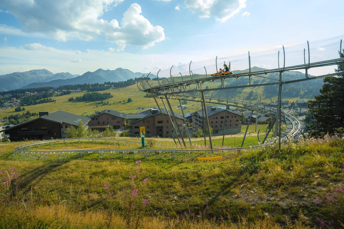 Structure de la luge sur rail au premier plan, village des Saisies et chaîne des Aravis derrière