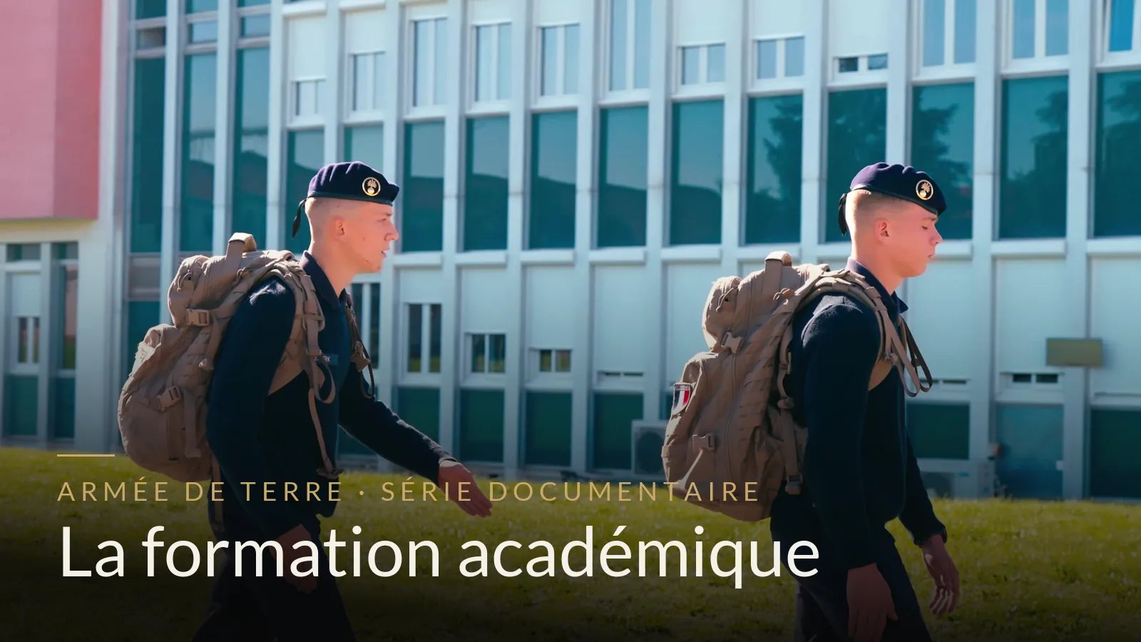 Deux jeunes engagés en tenue bleue, sac sur le dos, devant un bâtiment d'enseignement
