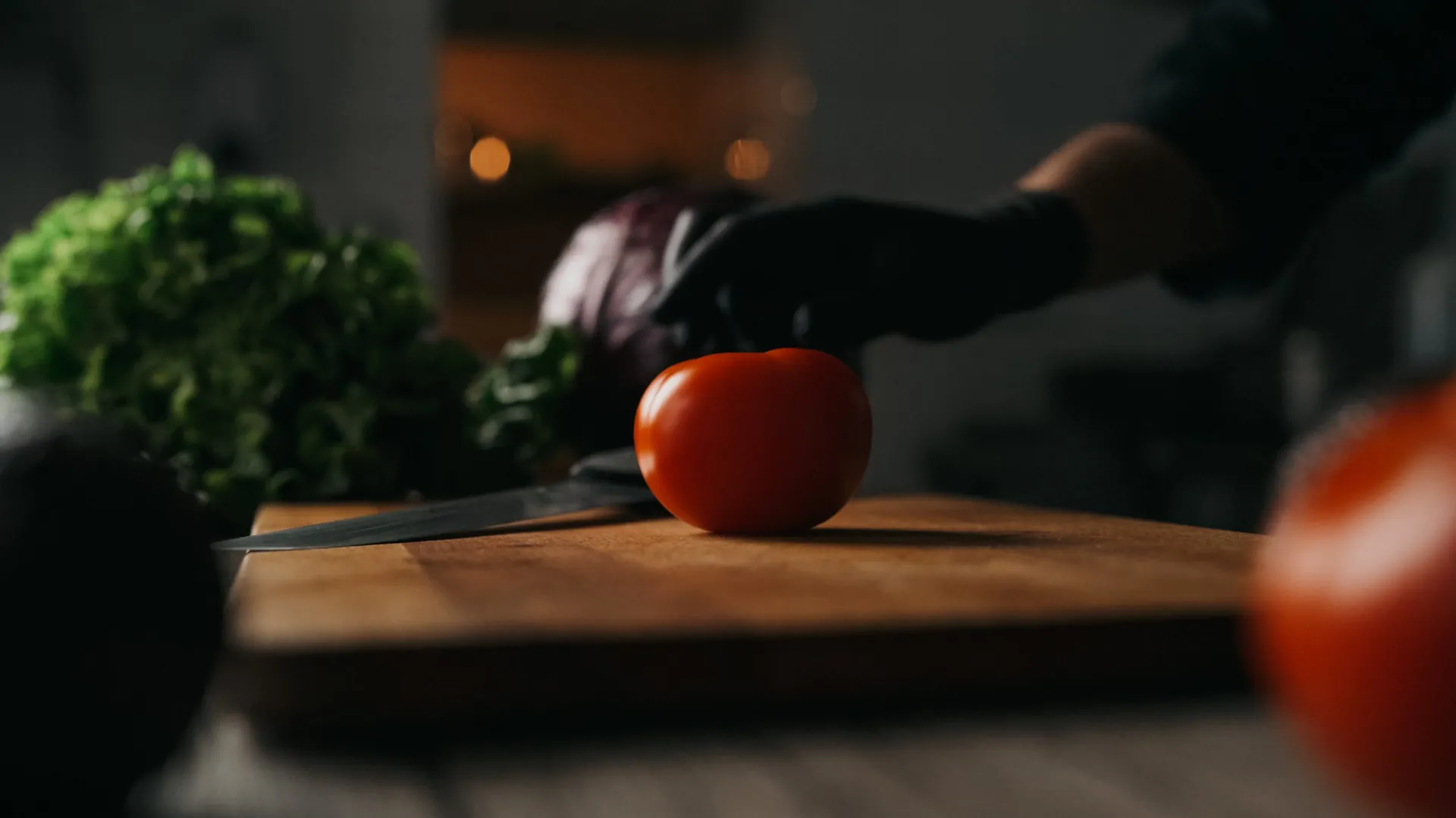 Une tomate sur la planche à découper, cuisine du restaurant dans la pénombre