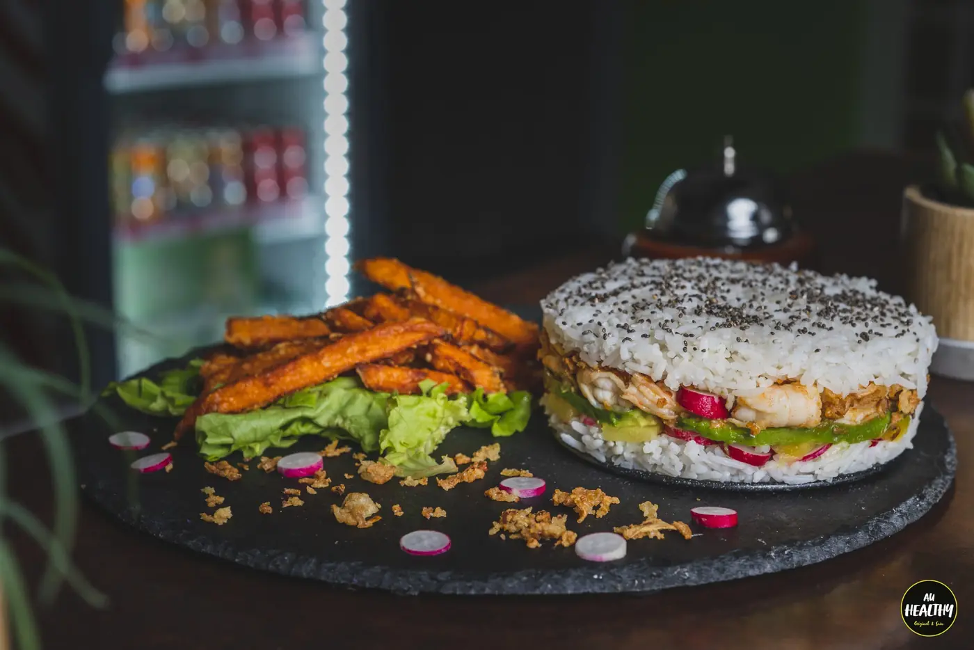 Burger de riz et frites de patate douce servis sur ardoise, fond sombre