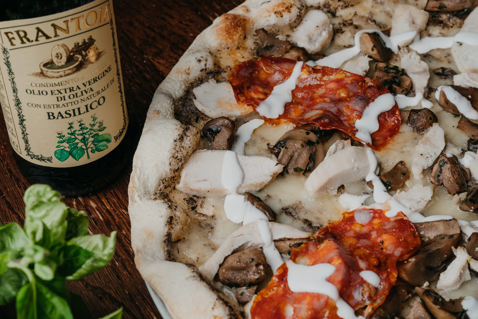 Pizza aux champignons et chorizo sur une planche en bois, bouteille d'huile d'olive au basilic, restaurant La Scala à Vierzon