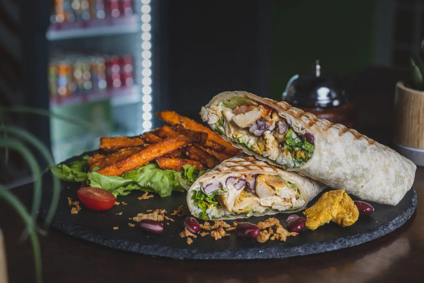 Wrap grillé et frites de patate douce sur ardoise, garniture visible à la coupe