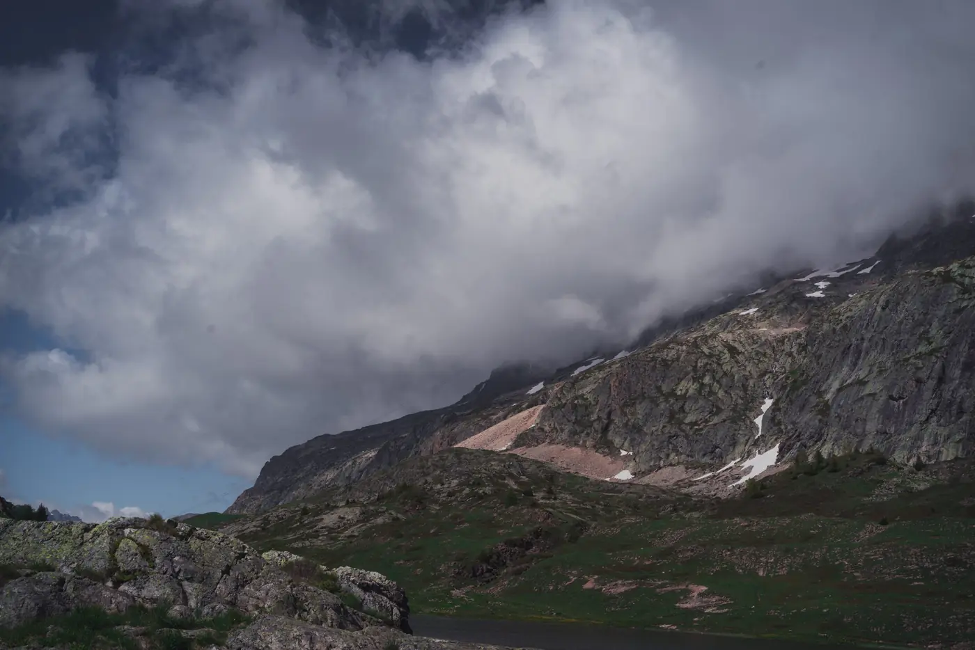Nuages d'orage accrochés à une crête rocheuse, pelouse alpine au premier plan