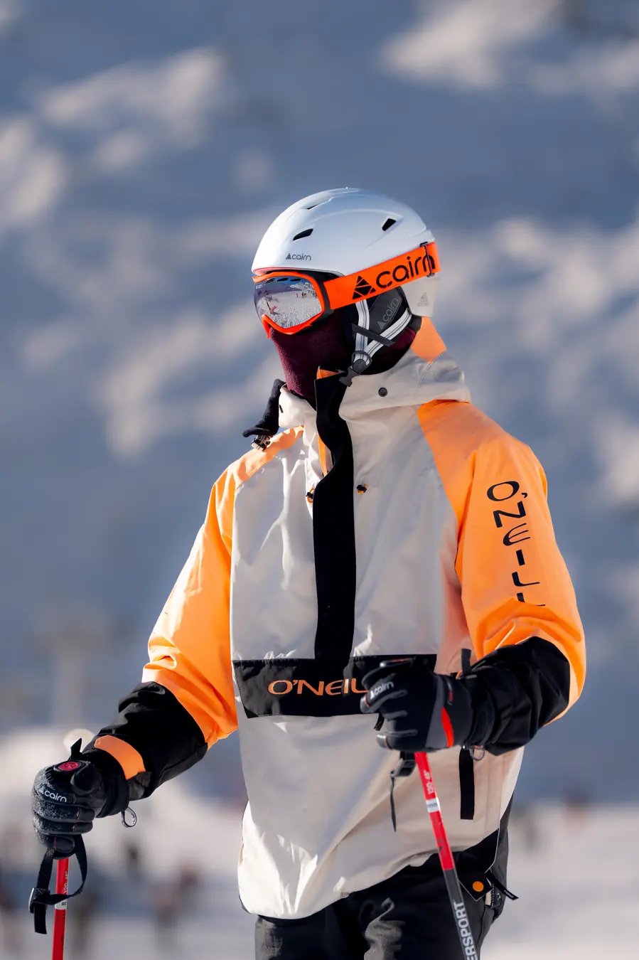Skieur en veste orange, masque et cagoule, bâtons en main, Val Thorens