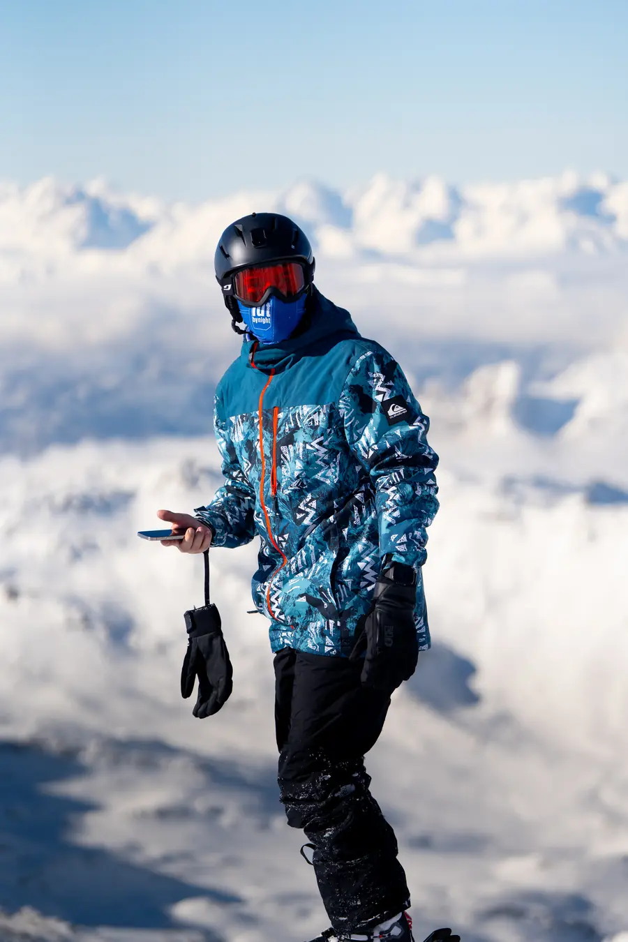 Skieur en veste bleue imprimée face aux sommets enneigés de Val Thorens