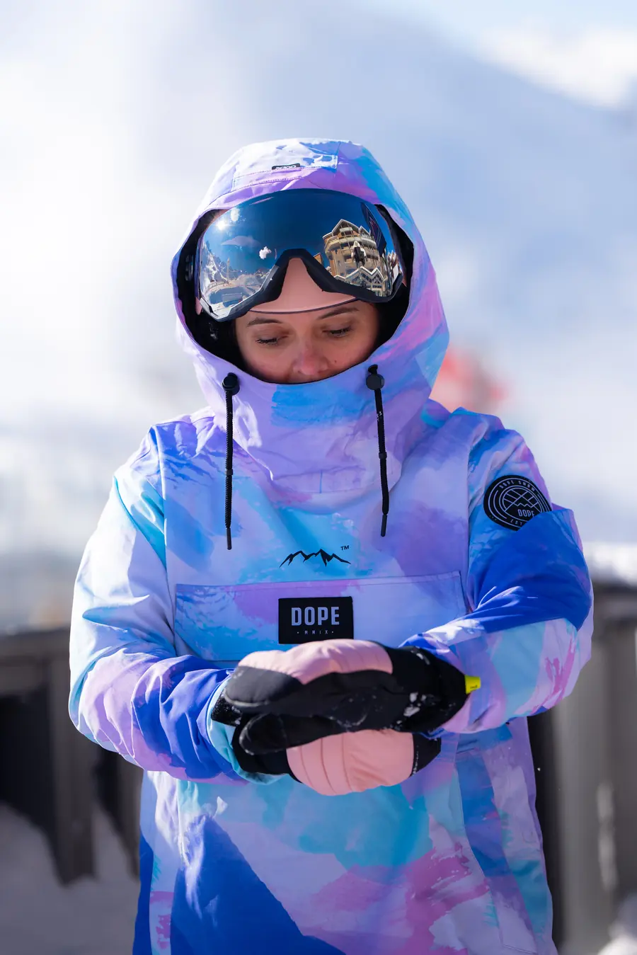 Skieuse en sweat pastel qui regarde sa montre en haut des pistes de Val Thorens