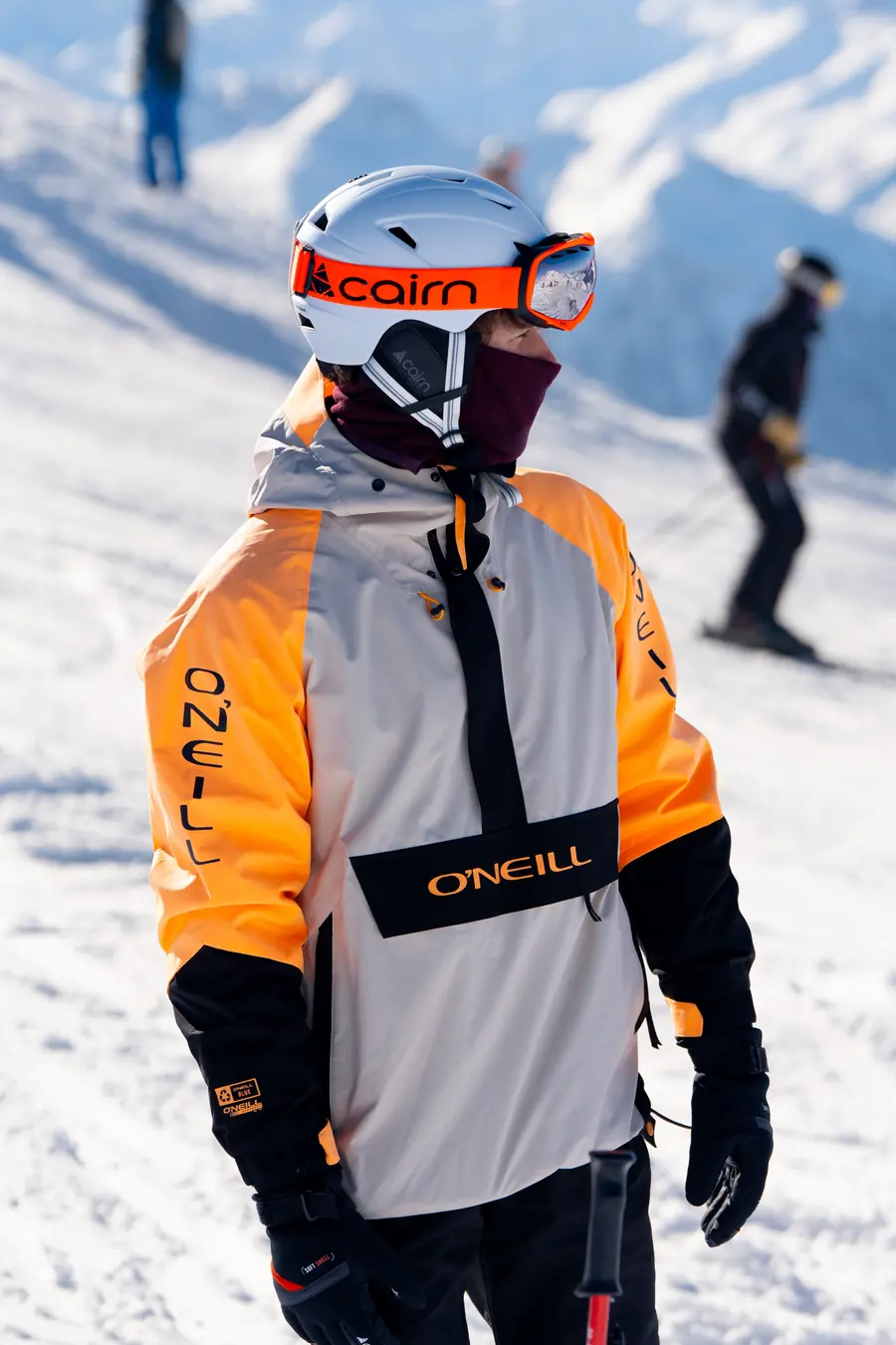 Skieur en veste orange et blanche sur une piste de Val Thorens, un autre skieur en contrebas