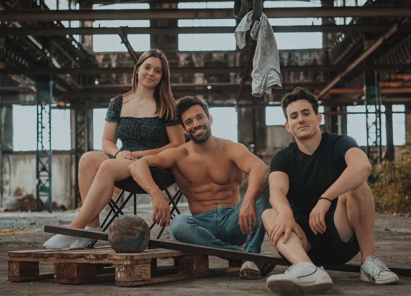 L'équipe du tournage assise sur des palettes dans la friche industrielle, l'artiste au centre