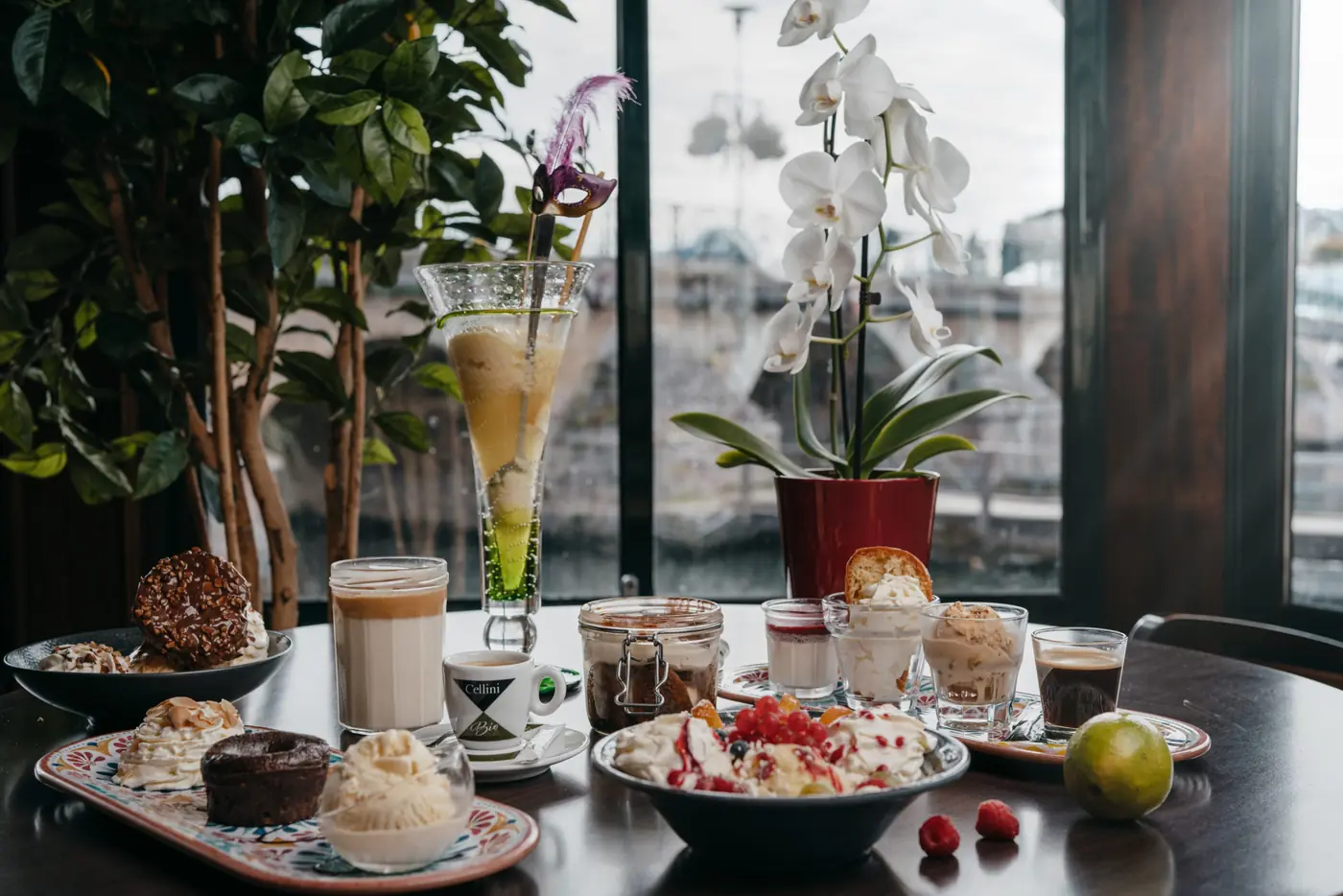 Table de desserts devant la baie vitrée : coupes glacées, cafés gourmands et orchidée blanche