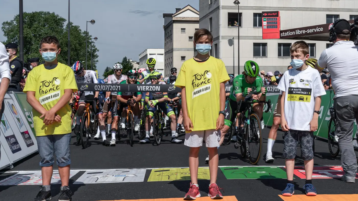 Trois enfants devant les coureurs sur la ligne de départ du Tour à Vierzon