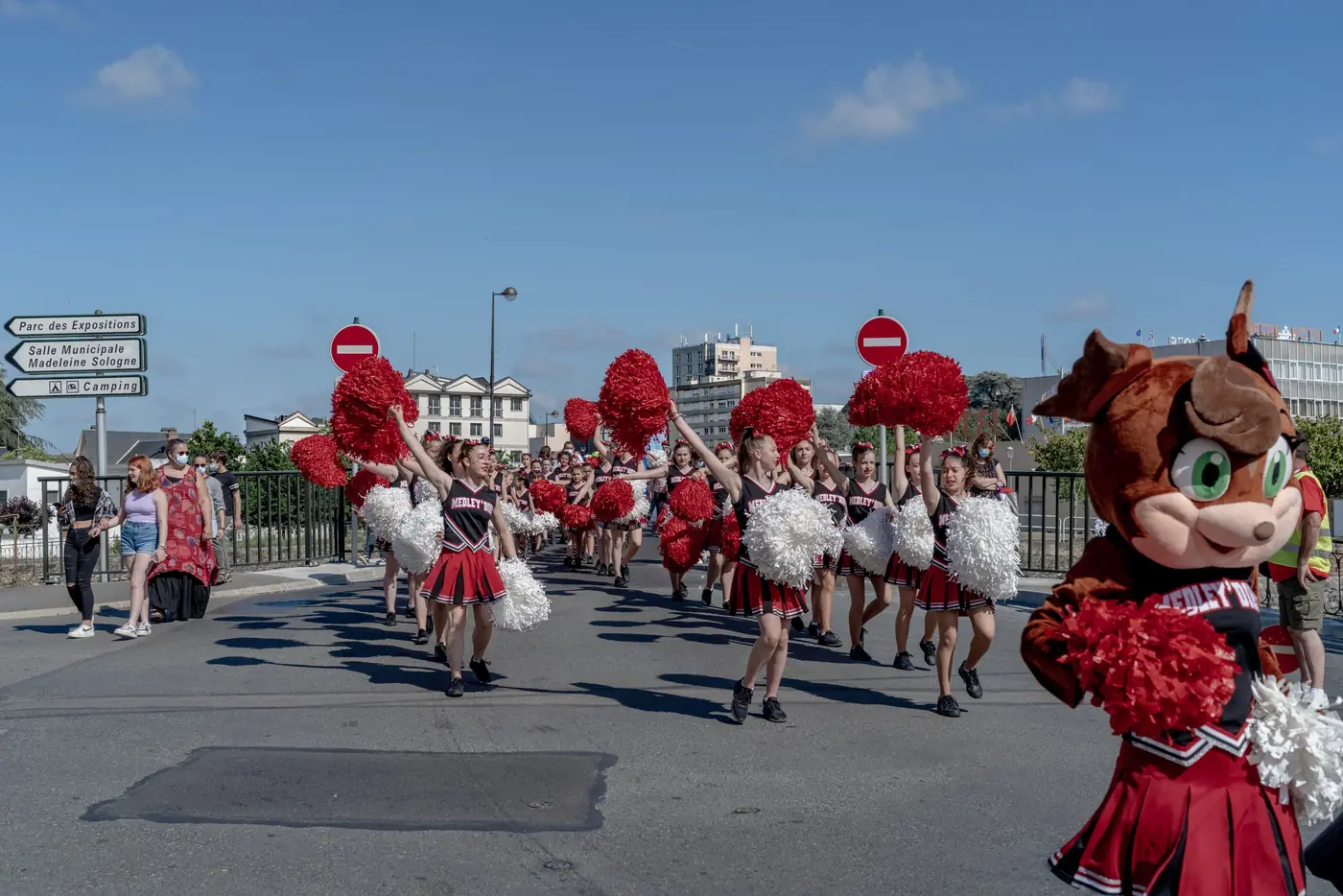 Majorettes aux pompons rouges et mascotte défilant dans une rue de Vierzon avant le départ