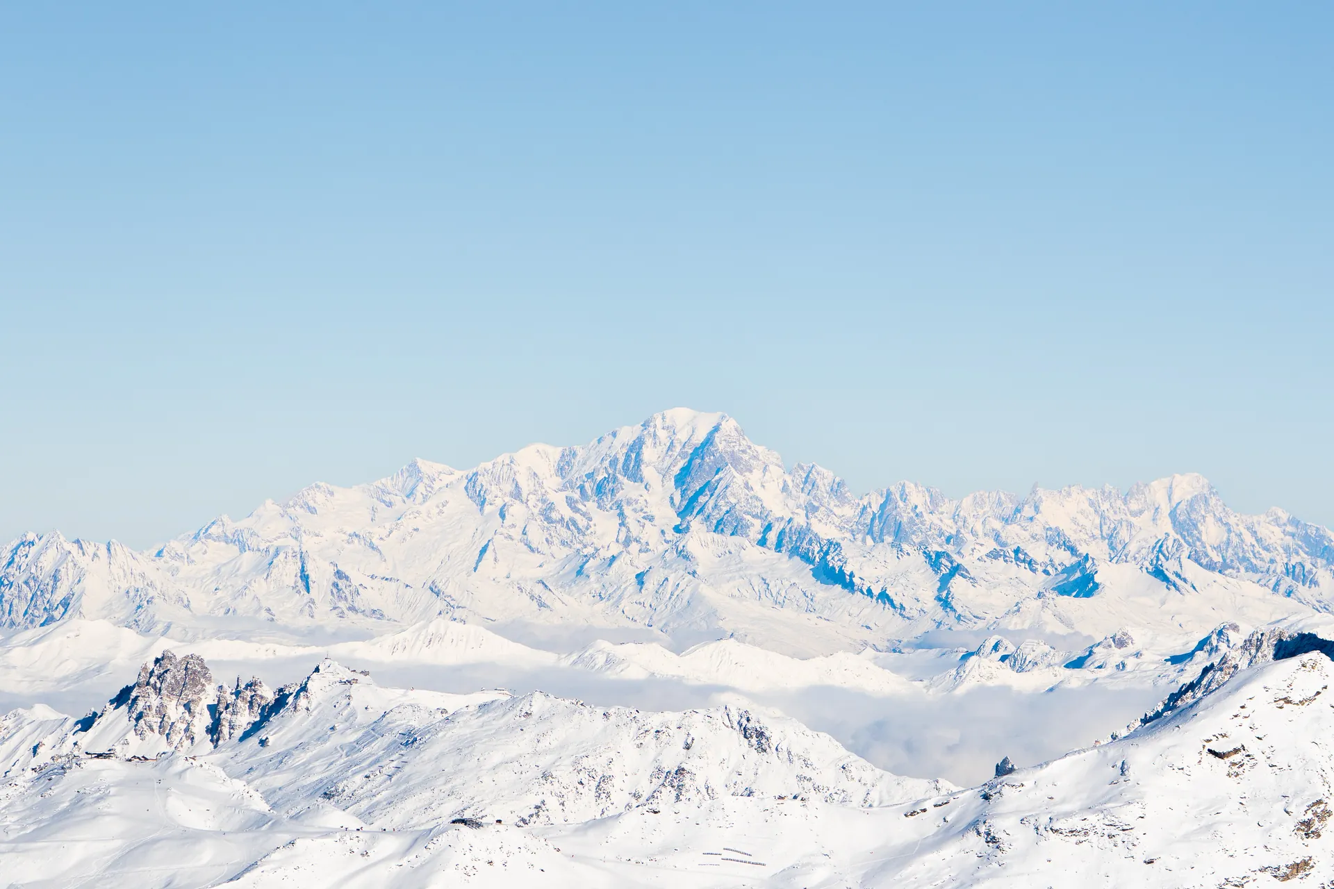 Massif de haute montagne enneigé au-dessus d'une mer de nuages, vu depuis les sommets de Val Thorens