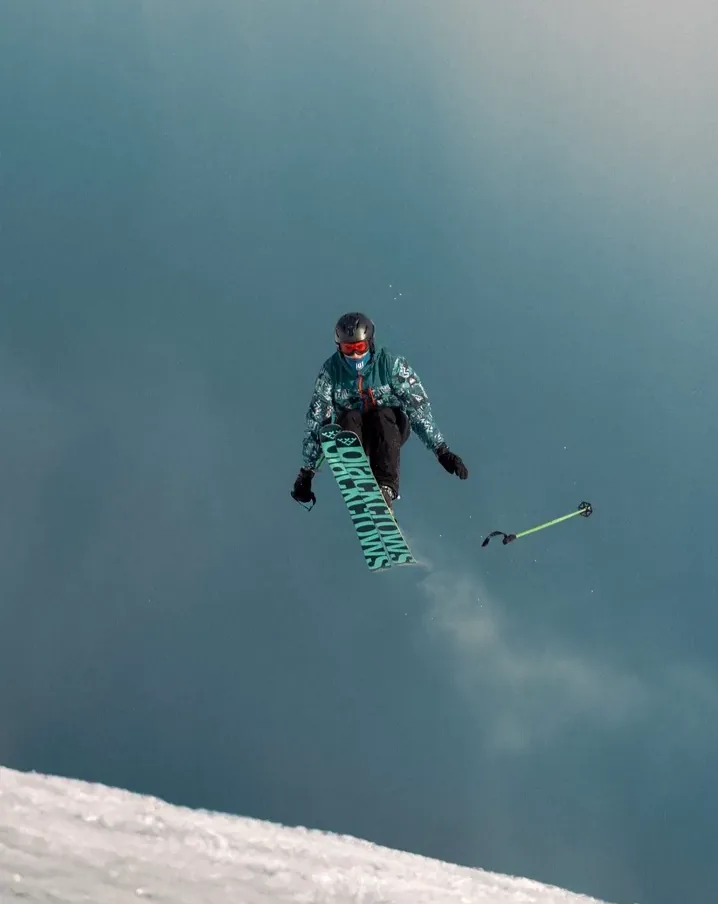 Skieur en plein saut au-dessus de la neige, bâtons écartés, à Val Thorens